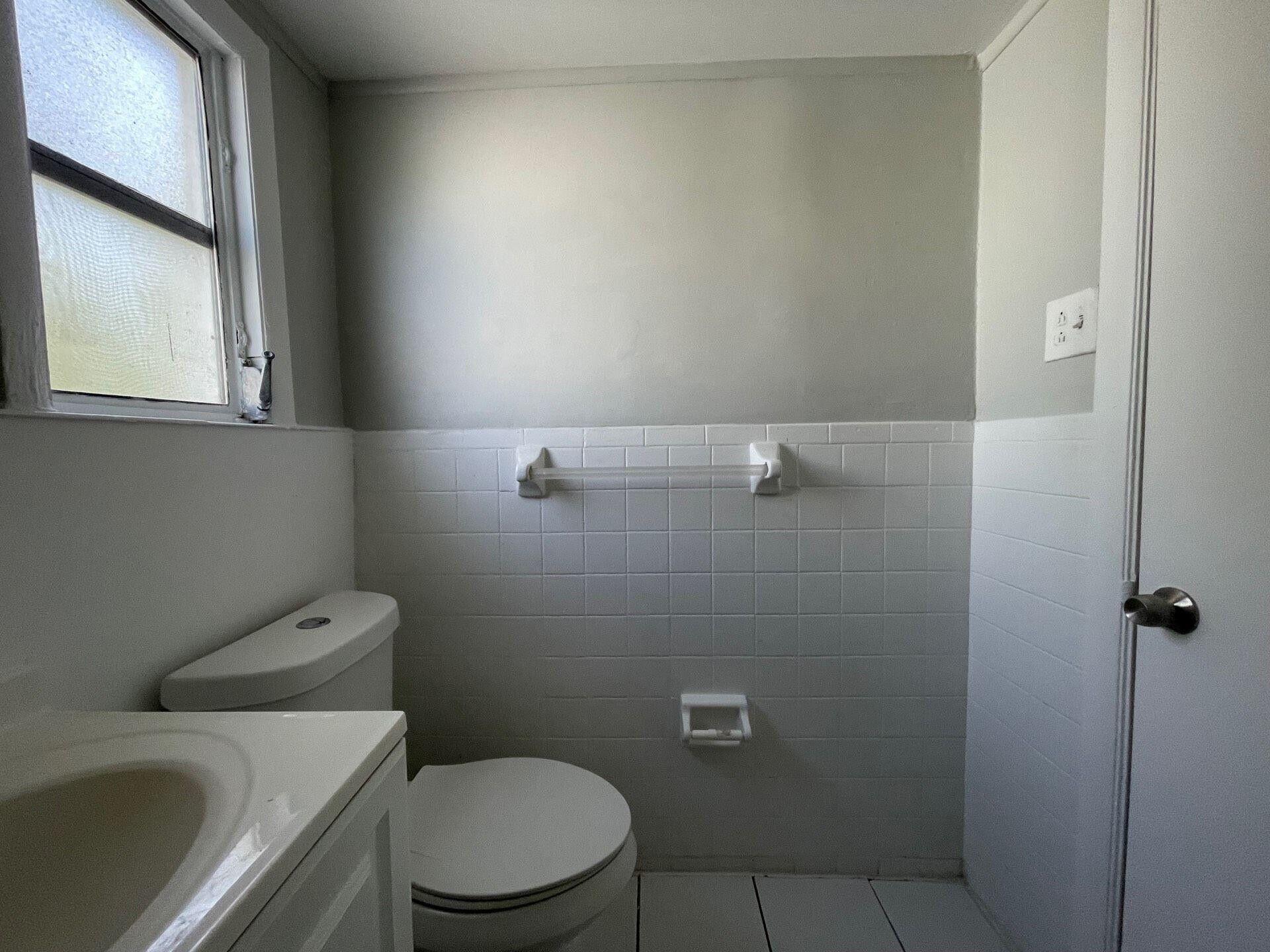 736 Omar Road, Unit 1 West Palm Beach, FL 33405 - Photo 20 of 25 a white toilet sitting next to a window and a sink