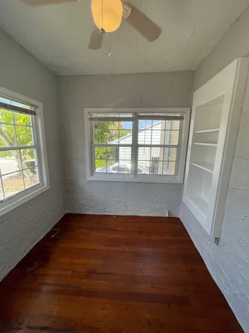 a view of an empty room with wooden floor and a window