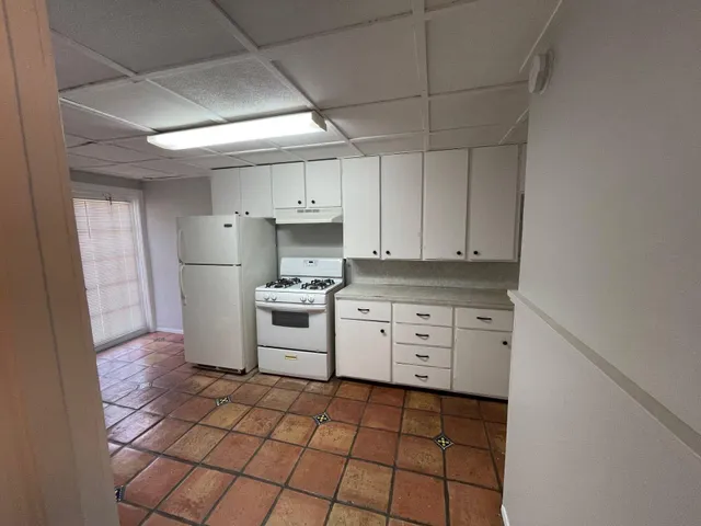 a kitchen with white cabinets a stove a sink and a refrigerator