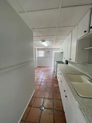 a kitchen with granite countertop a sink a counter top space and cabinets