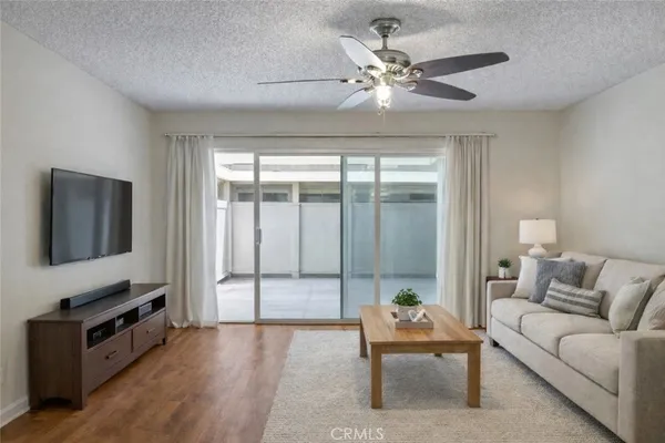 a living room with furniture a flat screen tv and a ceiling fan