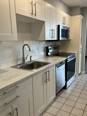 a kitchen with stainless steel appliances white cabinets a sink and a stove