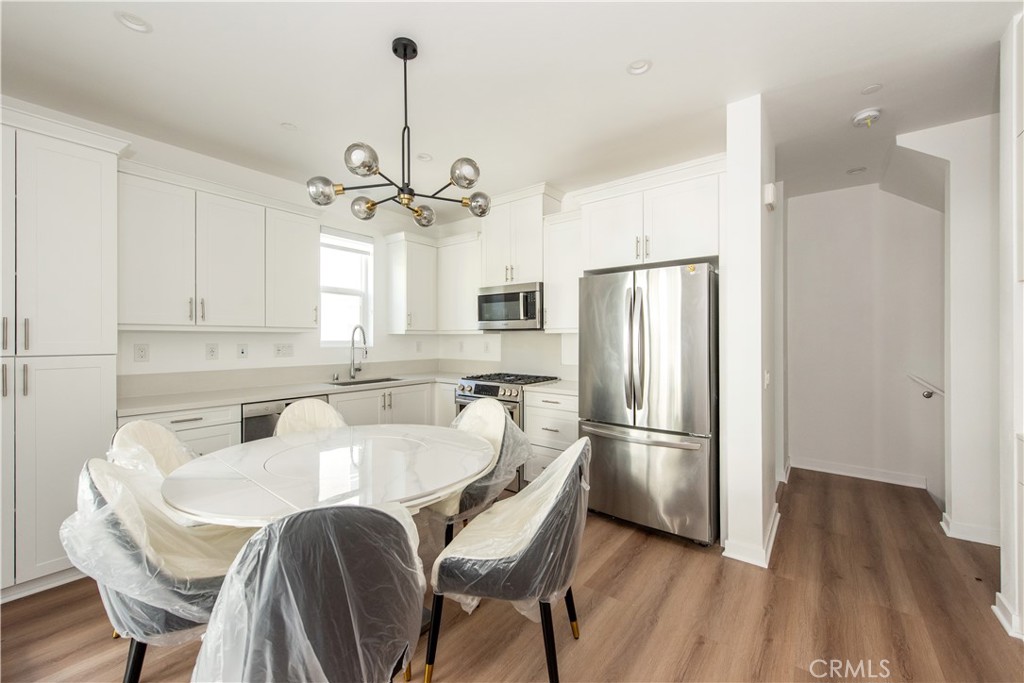 2208 Synergy Irvine, CA 92614 - Photo 7 of 22 a kitchen with stainless steel appliances granite countertop a refrigerator a sink dishwasher a stove and white cabinets with wooden floor