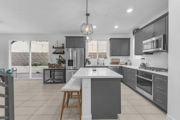 a kitchen with stainless steel appliances a stove a sink a refrigerator and chairs