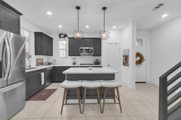 a kitchen with stainless steel appliances granite countertop a stove top oven a sink dishwasher a dining table and chairs with wooden floor