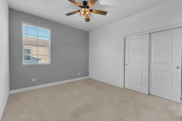 an empty room with windows and chandelier fan