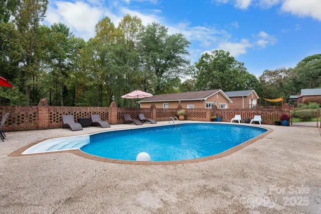 a view of a swimming pool with lawn chairs and a big yard