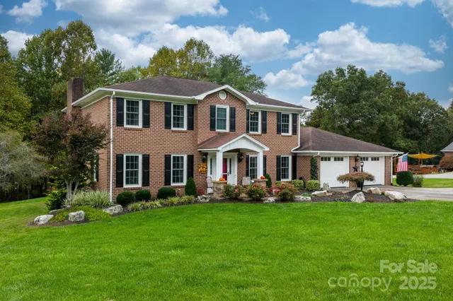 a front view of a house with garden and trees