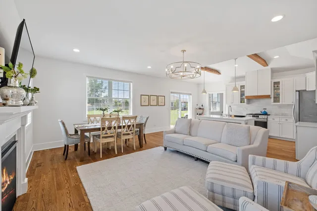 a living room with furniture a fireplace and a dining table with wooden floor