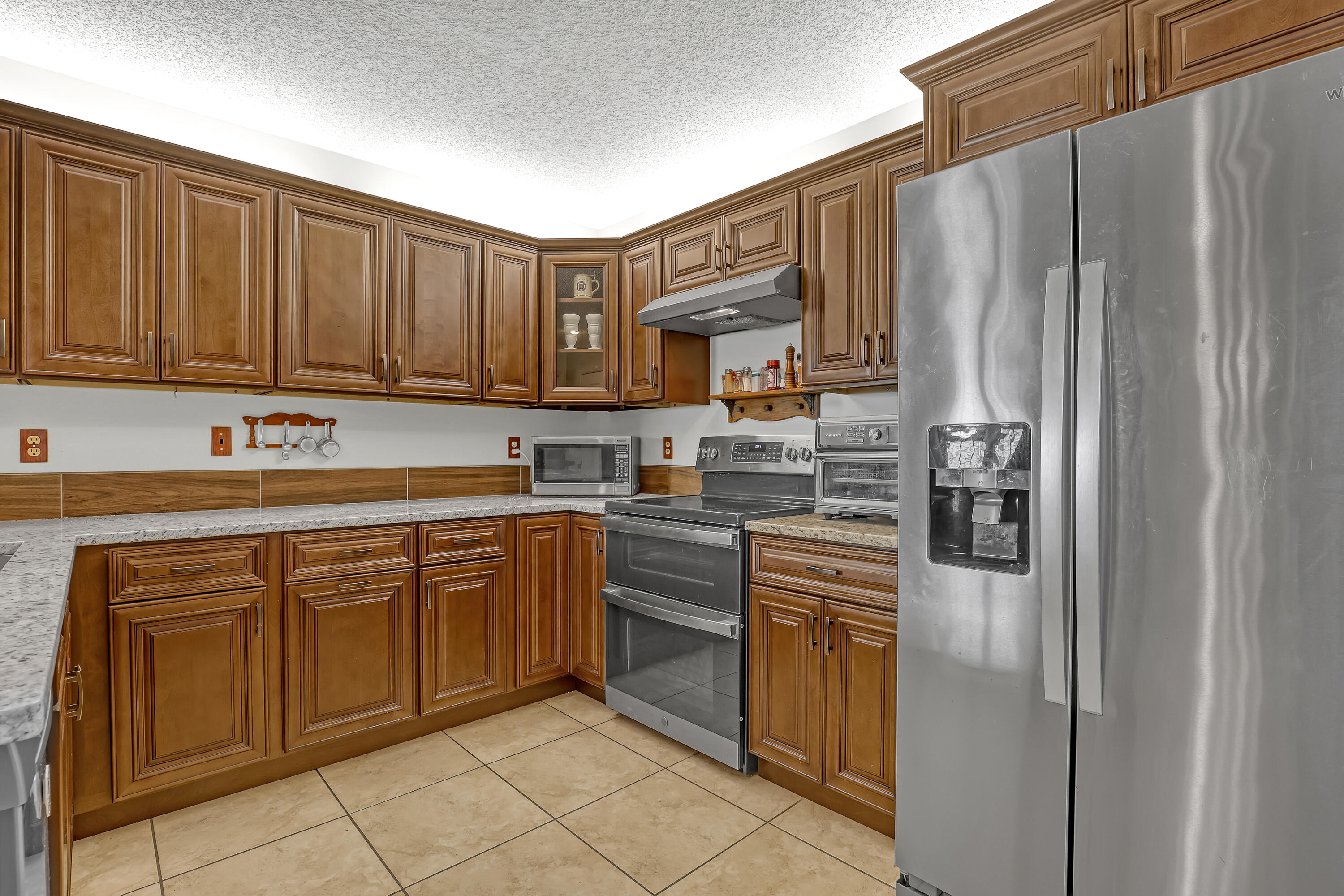 13116 Quiet Woods Road, Unit A Wellington, FL 33414 - Photo 12 of 31 a kitchen with stainless steel appliances granite countertop a refrigerator sink and cabinets