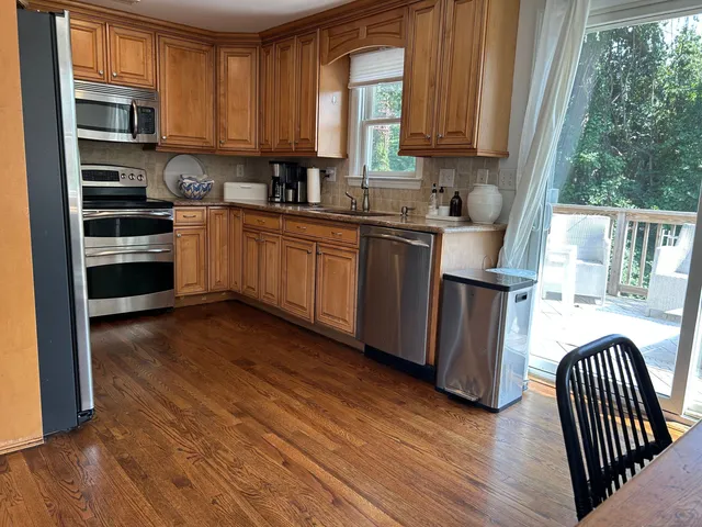 a kitchen with stainless steel appliances a sink a stove a refrigerator cabinets and a window