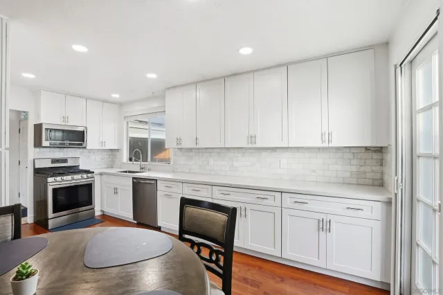 a kitchen with white cabinets stainless steel appliances and wooden floor