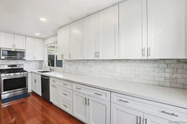 a kitchen with granite countertop white cabinets and stainless steel appliances