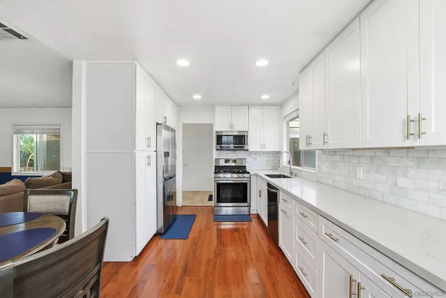 a large kitchen with stainless steel appliances granite countertop a refrigerator and a stove top oven