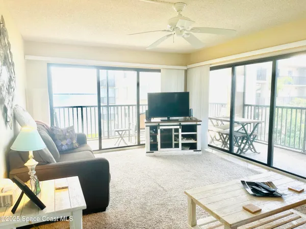 a living room with furniture a flat screen tv and a floor to ceiling window