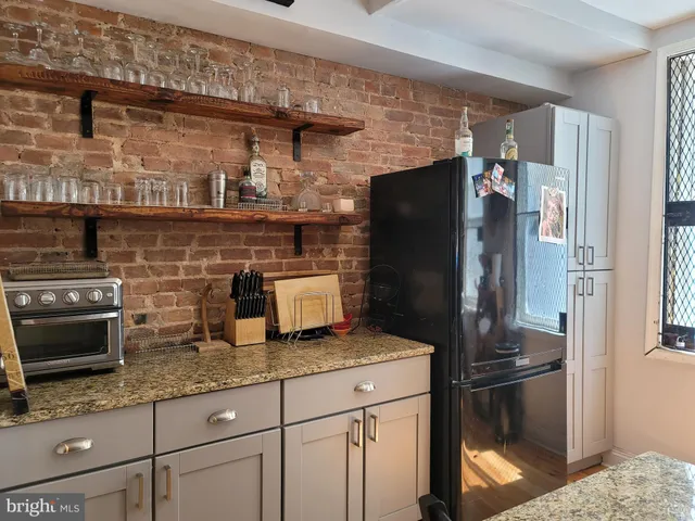 a kitchen with granite countertop a refrigerator and a stove top oven