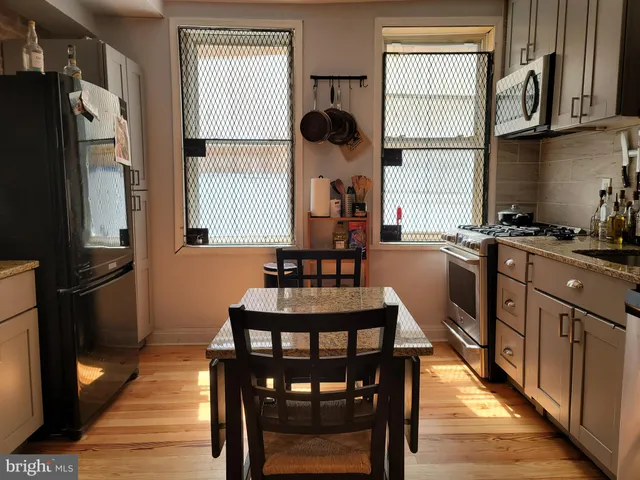 a kitchen with stainless steel appliances granite countertop a stove a refrigerator a sink dishwasher a dining table and chairs with wooden floor