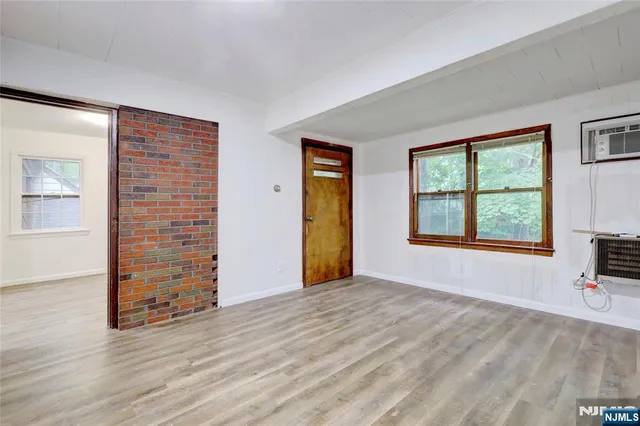 a view of an empty room with a window and wooden floor