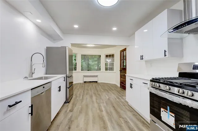 a kitchen with a stove a sink and a wooden floor