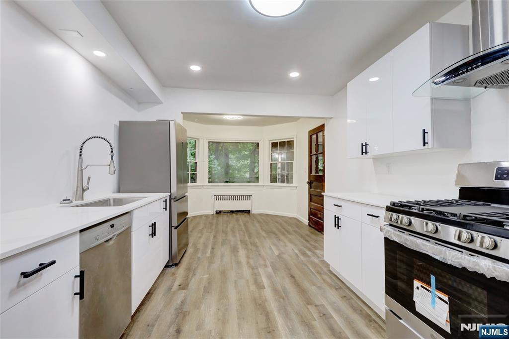 4-21 Saddle River Road, Unit 1 Fair Lawn, NJ 07410 - Photo 4 of 19 a kitchen with a stove a sink and a wooden floor