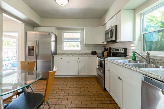 a kitchen with stainless steel appliances granite countertop a sink a stove top oven a counter space and cabinets