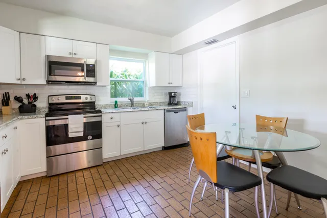 a kitchen with stainless steel appliances a stove a sink cabinets and a dining table