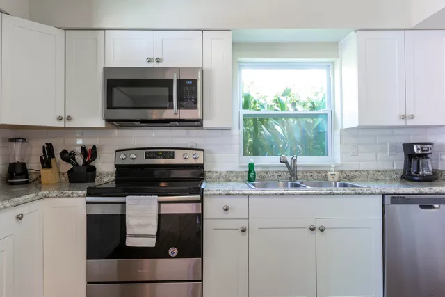 a kitchen with stainless steel appliances granite countertop a sink a stove a microwave and window