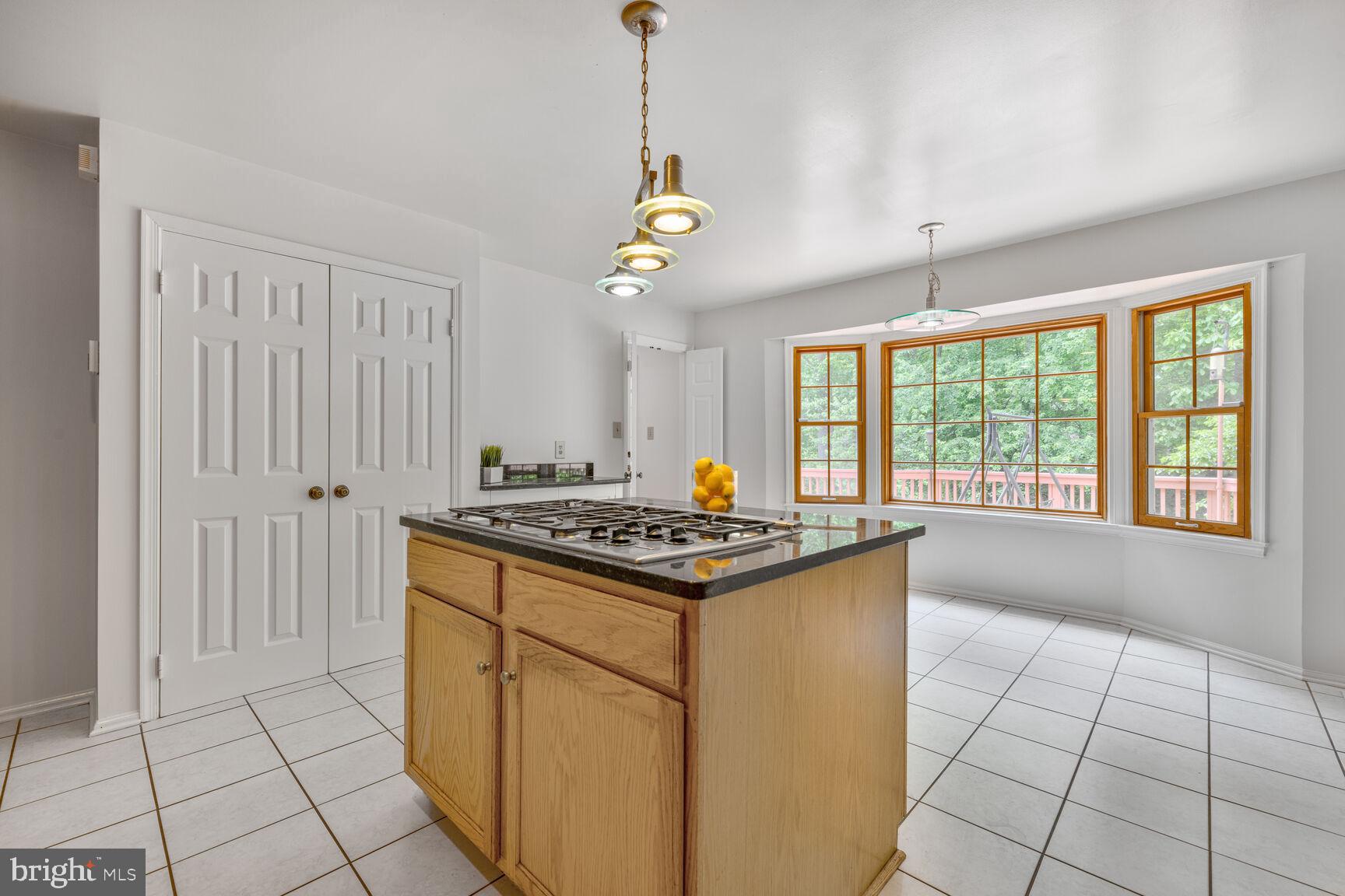 9605 Reach Road Potomac, MD 20854 - Photo 11 of 44 a kitchen with kitchen island granite countertop a stove a sink a counter top space and living room view