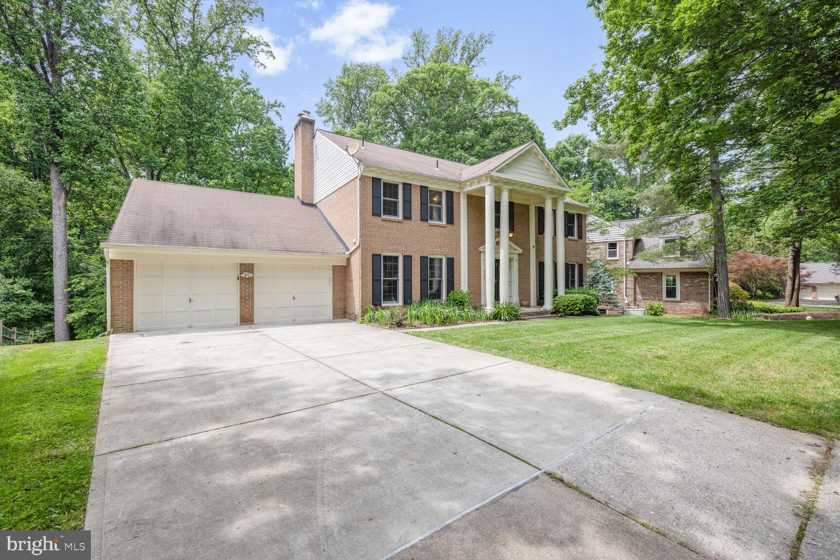 9605 Reach Road Potomac, MD 20854 - Photo 3 of 44 a front view of a house with a garden and trees