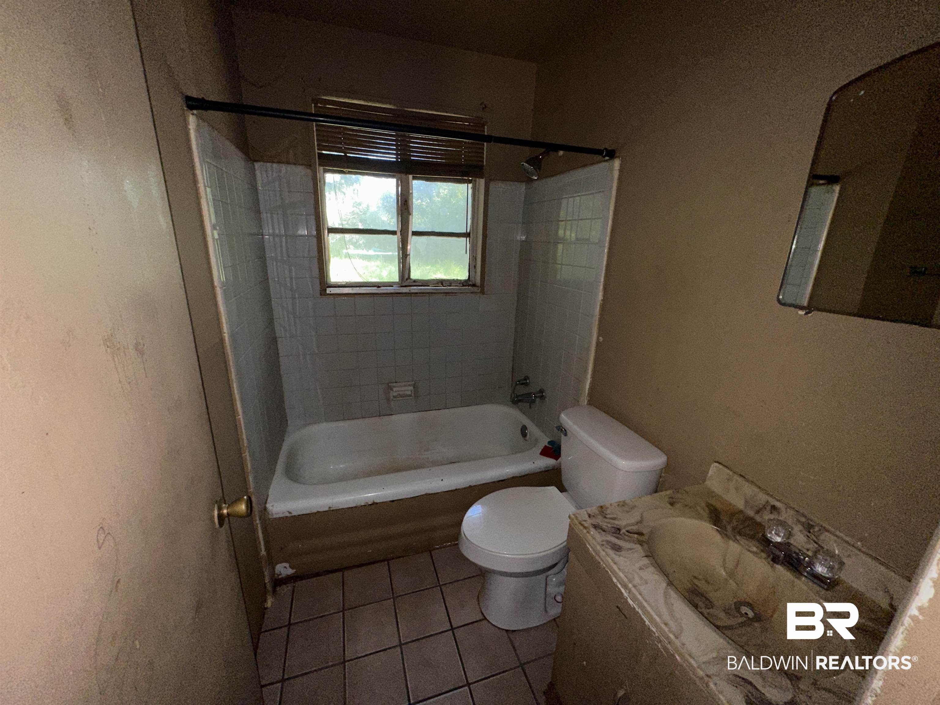58 Chieftain Way Mobile, AL 36611 - Photo 9 of 12 Full bathroom with tiled shower / bath combo, tile patterned flooring, toilet, and vanity