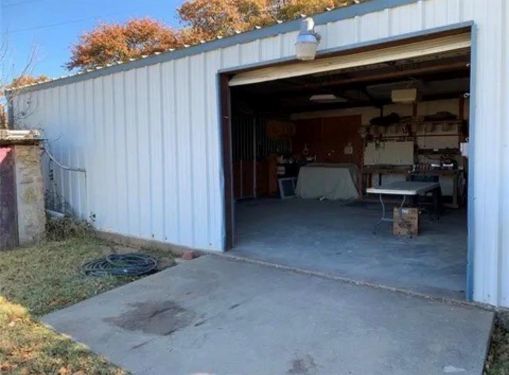 1794 Cr 527 Road Baird, TX 79504 - Photo 7 of 38 Metal-sided auxiliary building with a roll-up door, exterior lighting, and a concrete pad