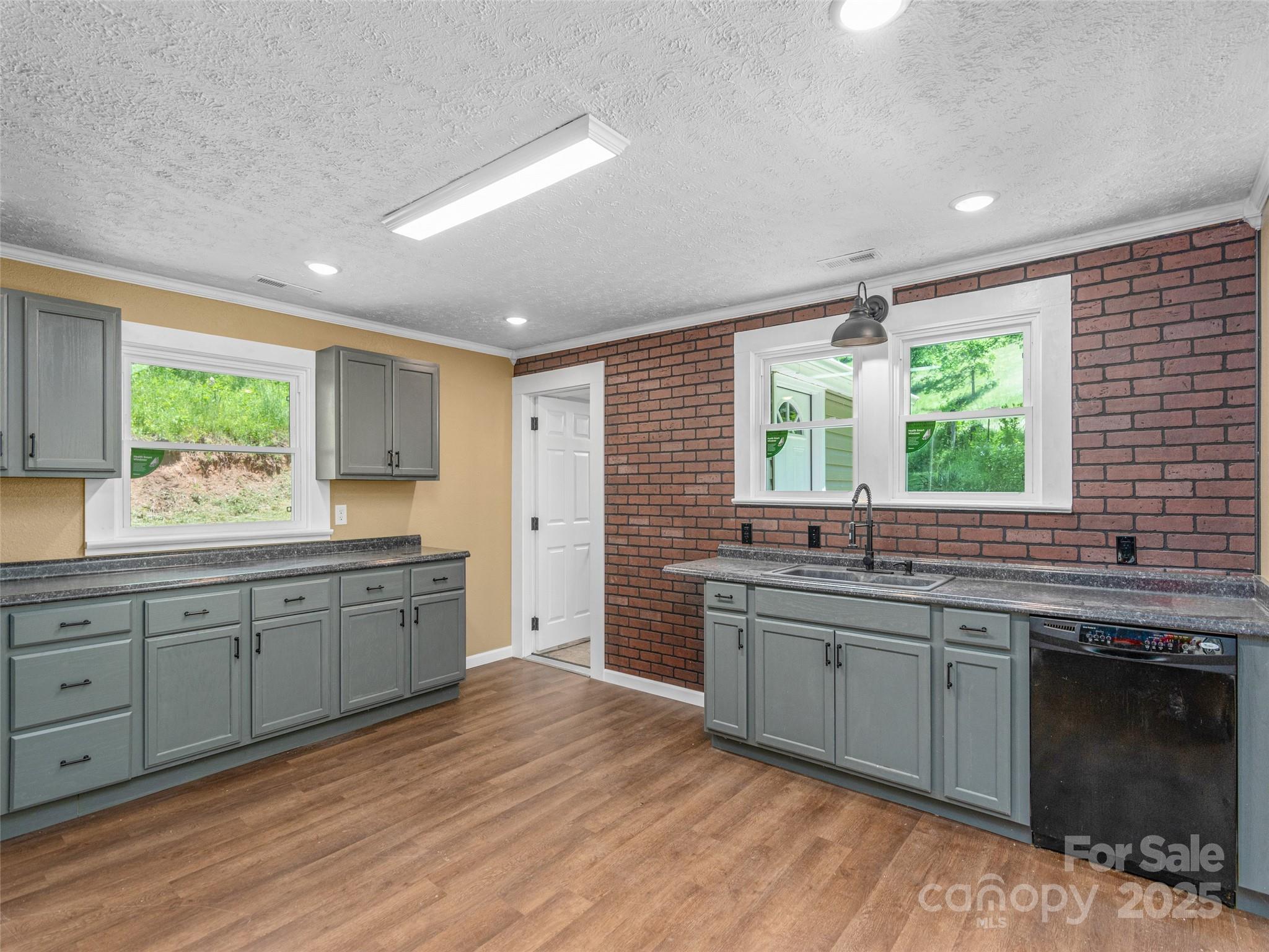 280 Noland Drive Clyde, NC 28721 - Photo 12 of 32 a large kitchen with stainless steel appliances granite countertop a sink dishwasher a stove a washer dryer and a dining table with wooden floor
