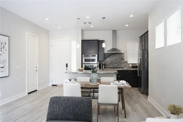 a kitchen with stainless steel appliances kitchen island granite countertop a dining table chairs and a refrigerator
