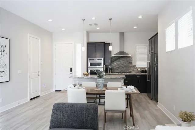 a kitchen with stainless steel appliances kitchen island granite countertop a dining table chairs and a refrigerator