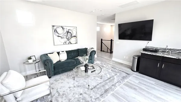 a living room with furniture a flat screen tv and a refrigerator
