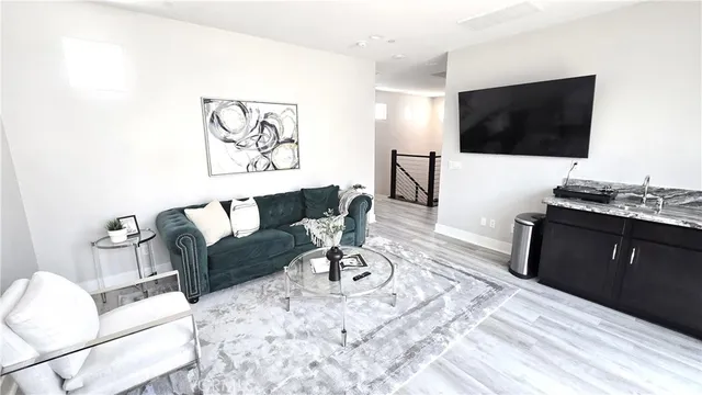 a living room with furniture a flat screen tv and a refrigerator