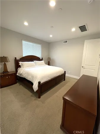 a spacious bedroom with a bed and lamp