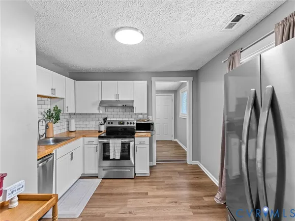 a kitchen with stainless steel appliances a refrigerator sink and white cabinets