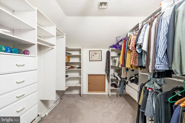 a view of walk in closet with clothes and shoes