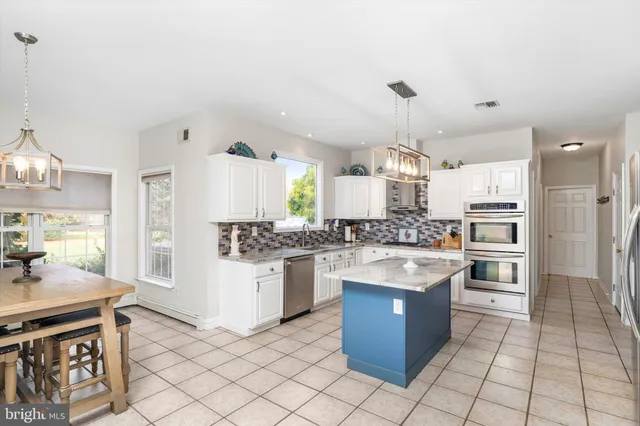 a large kitchen with granite countertop a stove oven and white cabinets