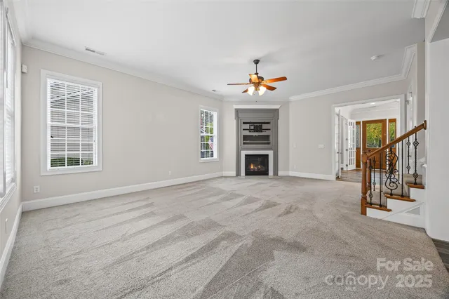 a view of an empty room with chandelier fan and windows