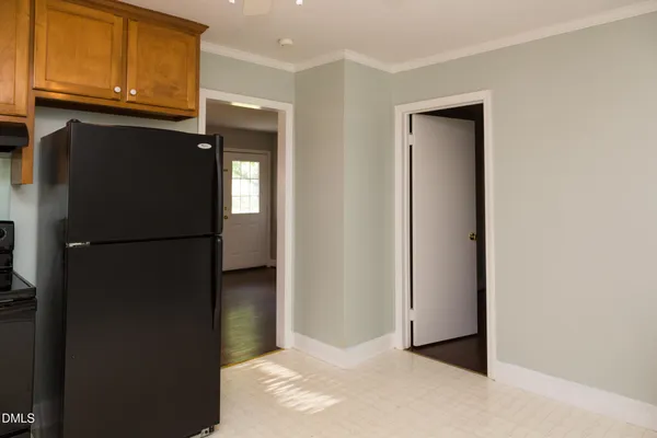 a view of a refrigerator in kitchen and an empty room