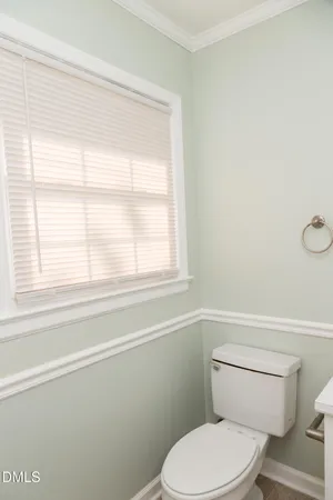 a white toilet sitting next to a window in a bathroom
