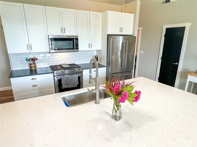 a kitchen with stainless steel appliances kitchen island granite countertop a white refrigerator a stove top oven a sink and dishwasher