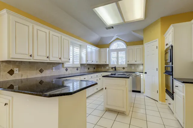 a kitchen with granite countertop white cabinets and white appliances