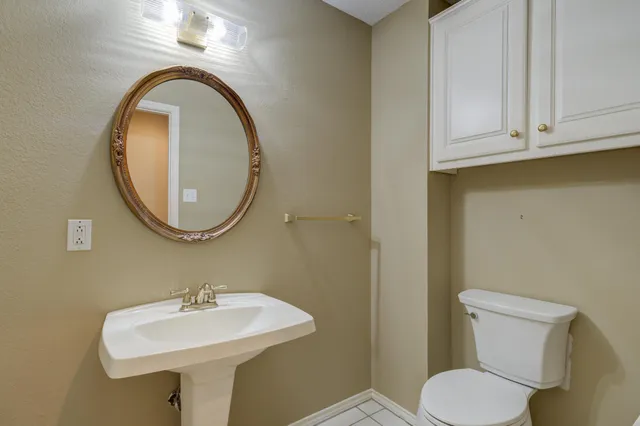 a view of an empty room with a chandelier fan and a bathroom