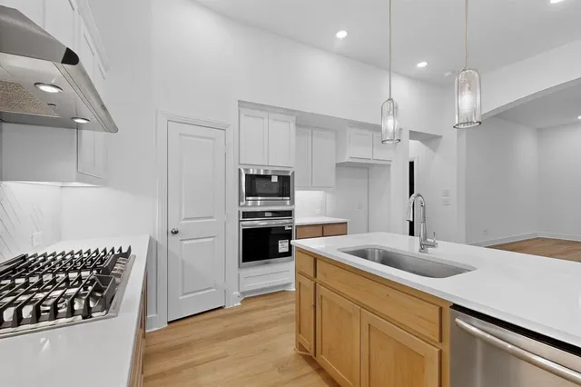 a kitchen with stainless steel appliances a sink a stove a refrigerator and cabinets