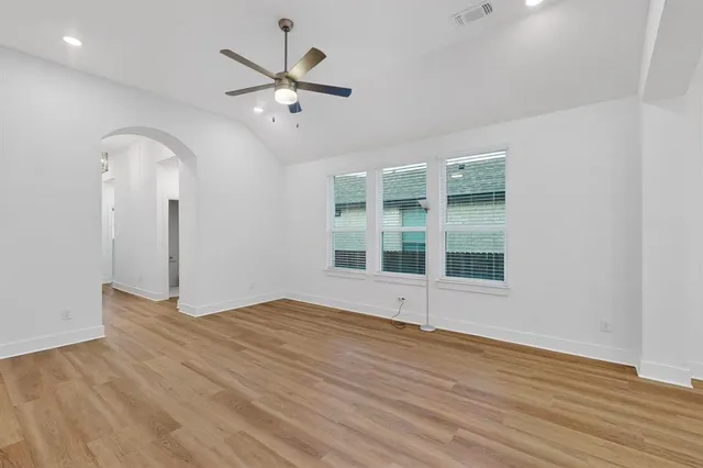 a view of an empty room with a window and wooden floor