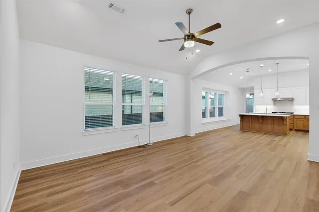 a view of an empty room with a window and wooden floor