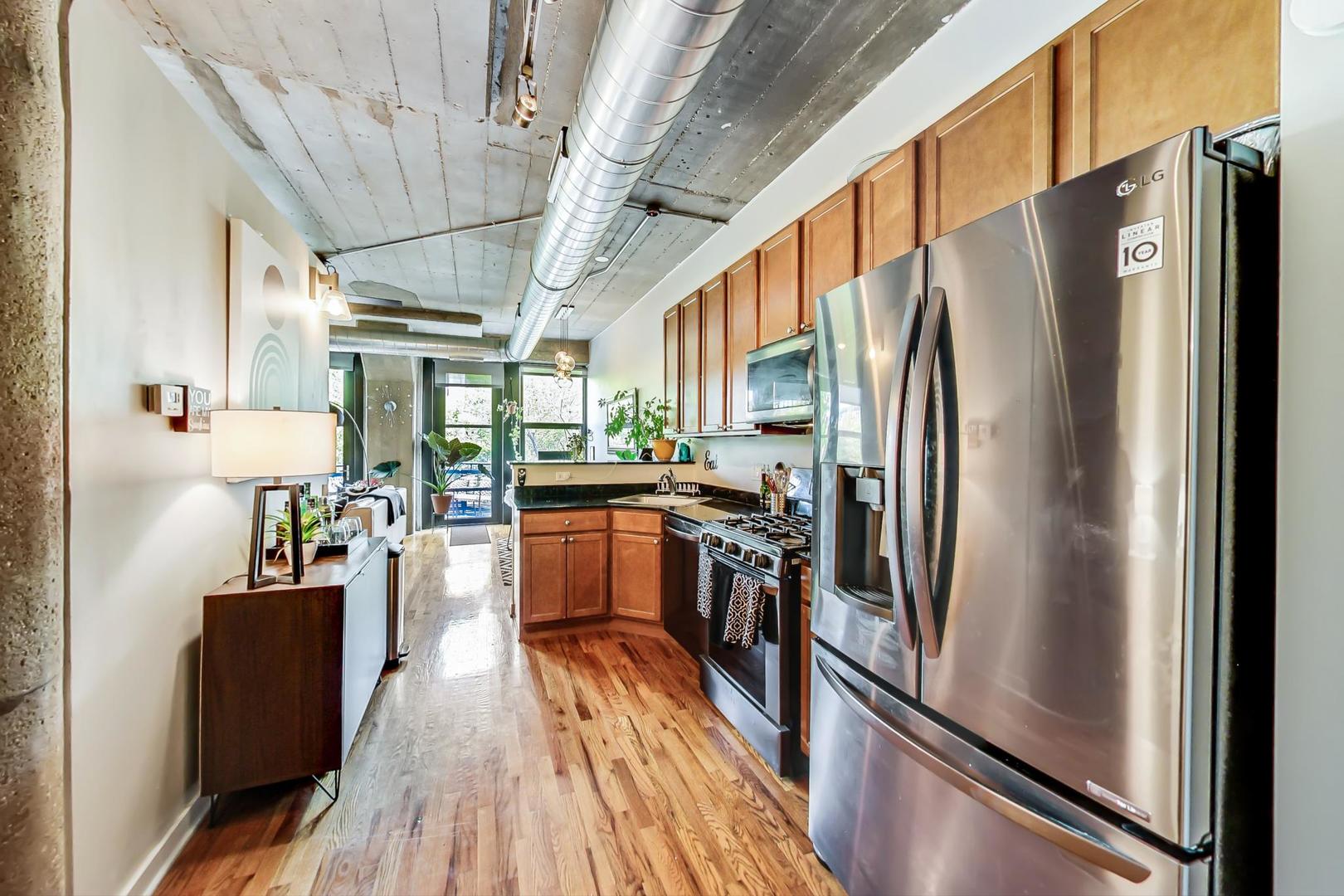 1111 West 15th Street, Unit 221 Chicago, IL 60608 - Photo 10 of 21 a kitchen with stainless steel appliances a refrigerator a stove a sink dishwasher a oven with wooden floor